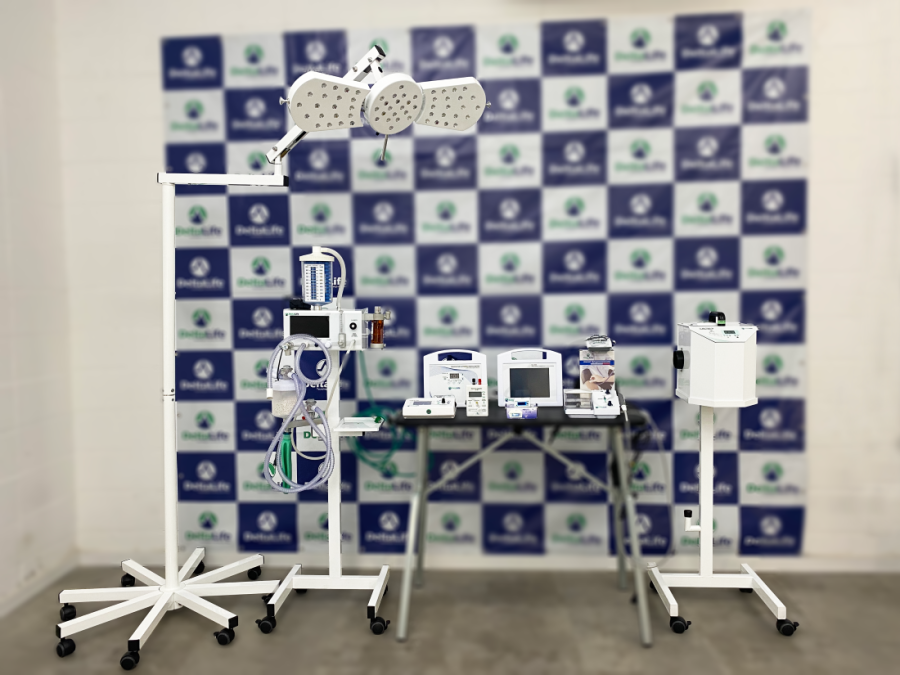 A imagem mostra um conjunto de equipamentos médicos e cirúrgicos de alta tecnologia, incluindo um aparelho de anestesia e monitores, dispostos em pedestais móveis. Eles são exibidos em frente a um painel de fundo estampado, sugerindo um stand de feira ou apresentação de centro cirurgico veterinário.